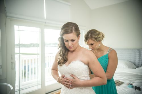 sister helping bride put on wedding gown new england wedding sea breaze inn rhode island